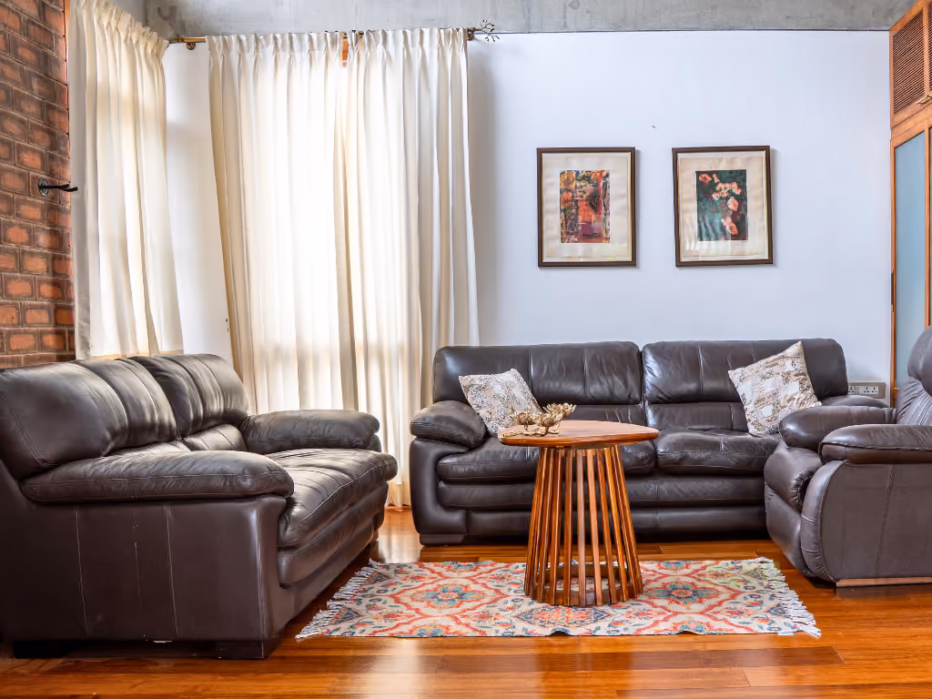 The lounge in the afternoon, deep sofas and two framed paintings, light through long curtains